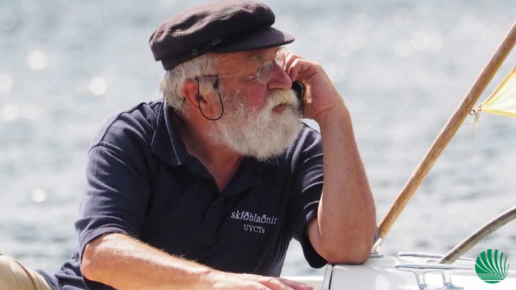 Ein Kapitän telefoniert, angelehnt an ein Boot